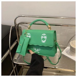 Detail of green skull print crossbody bag with detachable coin purse and metal handle