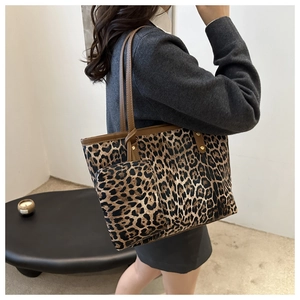 Detail van luipaardprint tote bag met bruine lederen handvaten en metalen klinknagel-accent