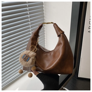 Detail of vintage brown hobo bag with gold metal handle and sheep plush charm