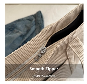 Close-up of smooth top zipper closure on a beige corduroy tote bag with thick texture