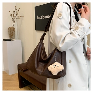Detail of dark brown faux leather tote with metallic zipper and plush pendant