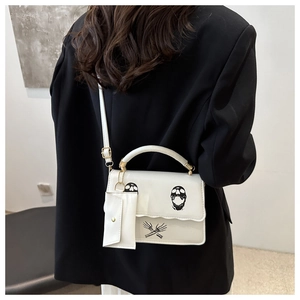 Detailed view of white shoulder bag with skull print and mini snap-button coin purse