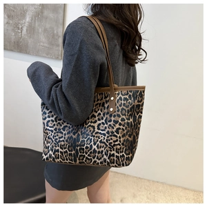 Leopard print tote bag with brown handles shown on shoulder for a stylish retro look