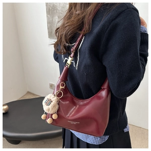Détail du sac demi-lune bordeaux avec bandoulière réglable et breloque mouton en peluche