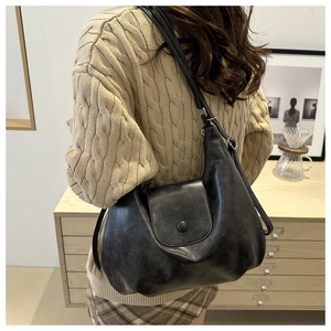 Detail of vintage black leather crossbody bag with magnetic buckle and soft texture