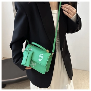 Detail of green skull print shoulder bag featuring a detachable mini square coin purse