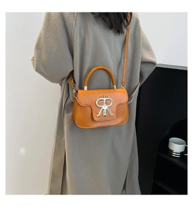 Detail der orangefarbenen Umhängetasche mit goldenem R-Logo in der Rückansicht am Model