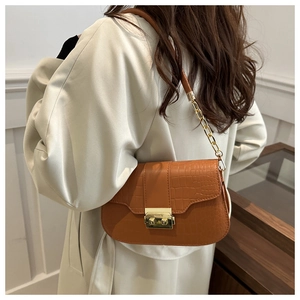 Brown crocodile embossed underarm bag with gold metal buckle shown on a trench coat