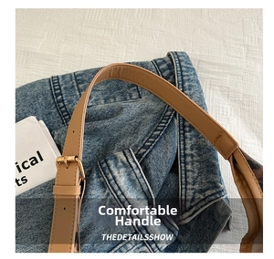 Détail d'une bandoulière réglable en cuir marron avec boucle en métal sur un sac en denim bleu