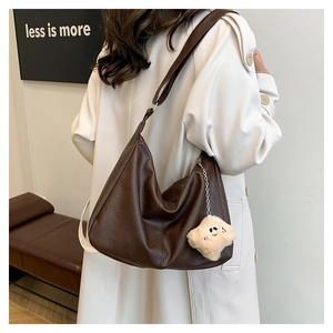 Detail of dark brown tote bag with leather texture and star charm on a casual model