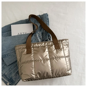 Detail of champagne gold quilted tote bag with brown woven straps and puffed air texture