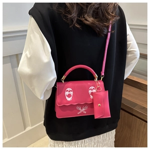 Detail of fuchsia skull print crossbody bag with matching mini pouch and gold hardware