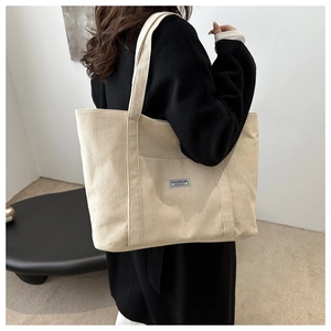 Detail of beige corduroy tote bag showing ribbed texture and fashion instinct label