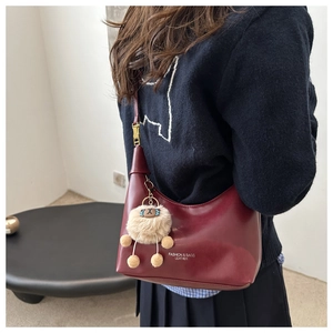Détail du sac demi-lune bordeaux avec breloque agneau en peluche et boucle dorée