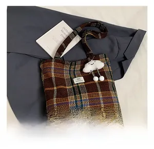 Detail showing checkered wool tote bag texture with plush cloud pendant and HOU patch