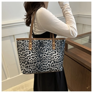 Detailed macro view of leopard print tote bag with brown leather handles and gold rivets
