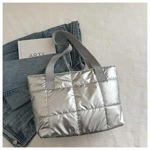 Close-up of silver quilted puffer tote bag with durable grey fabric handles