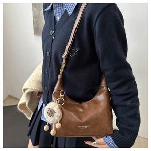 Détail d'un sac à bandoulière marron rétro avec charme mouton et texte imprimé