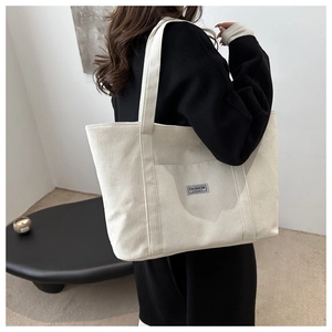 Detail of white corduroy tote bag showing ribbed texture and fashion instinct label