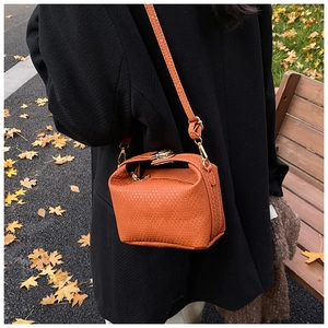 Vue détaillée d'un sac bandoulière orange avec texture tressée et fermoir métallique