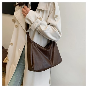 Detail of dark brown leather tote bag with vintage texture on beige trench coat