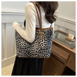 Close-up of leopard print tote bag with brown straps and metal rivet reinforcement
