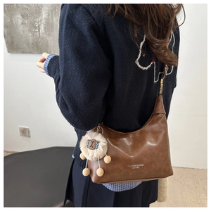 Detail of a brown leather dumpling bag with sheep charm and adjustable metal buckle