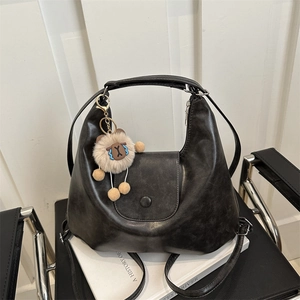 Retro black PU leather tote bag with a cute plush bear charm on a modern chair