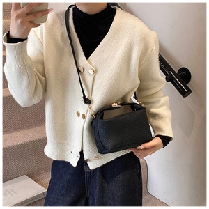 Détail de la texture tressée noire du sac à main avec fermoir doré et bandoulière