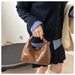 Détail du sac dumpling en cuir PU marron avec ornement sphérique sur la poignée