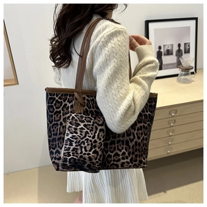 Detail of leopard print tote bag with small zip pouch shown on shoulder in cozy room