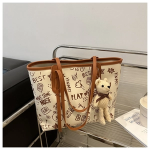 Detail of white tote bag with bear charm on a stand with indoor background