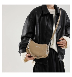 Detail of khaki crescent shoulder bag with metal chain strap and embossed lettering