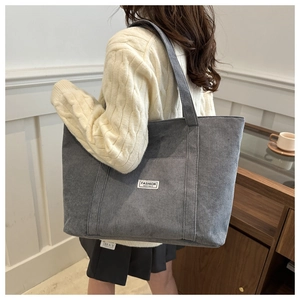 Detail of grey corduroy tote bag showing ribbed texture and minimalist front pocket label