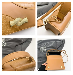Macro detail of brown leather bag with crocodile texture and gold wavy buckle