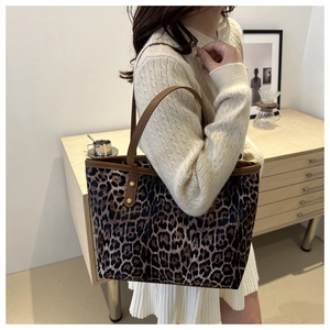 Detailopname van de grote luipaardprint tote bag met bruine riemen en gouden studs