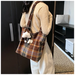Brown plaid tote bag with plush cloud charm shown on model in a soft indoor setting