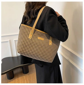 Detail of vintage houndstooth fabric and yellow leather strap on a large tote bag