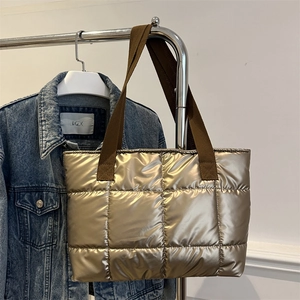 Chic gold quilted puffer tote bag with brown woven straps on a minimalist hanger