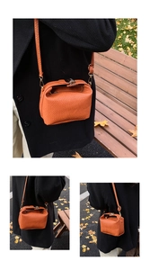 Détail d'un mini sac orange tressé avec boucle dorée dans un décor de parc automnal