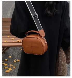 Brown litchi leather bag detail with cross stitching and black-white wide strap