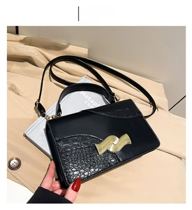 Détail du sac noir avec texture crocodile et boucle dorée au style vintage