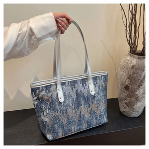 Detail view of navy sequined tote bag with silver handles and geometric pattern