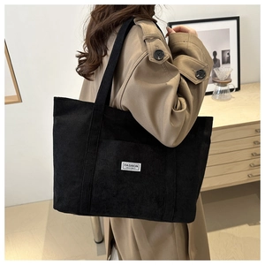 Detail view of black corduroy tote bag with Fashion Instinct label and wide strap
