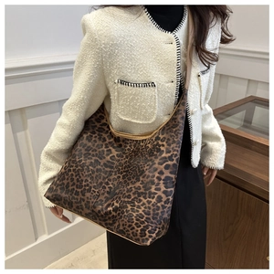 Vue détaillée du grand sac à main léopard porté avec un manteau blanc texturé moderne