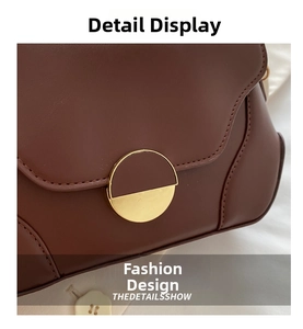 Detail of dark brown leather handbag with a circular gold metal clasp and smooth finish