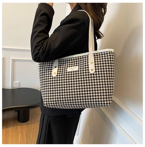 Detailed close-up of houndstooth tote bag with white leather straps and brand patch