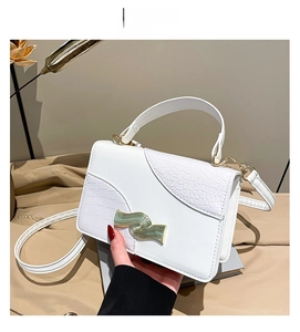 Détail du sac blanc avec rabat texture crocodile et fermoir métallique doré en forme d'onde
