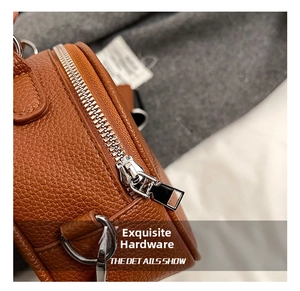 Close-up of brown lychee grain leather texture with shiny silver metal zipper and D-ring