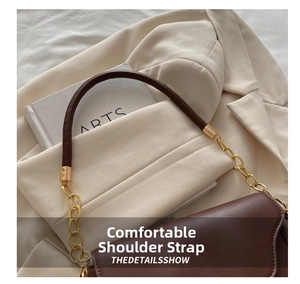 Detail of a brown leather handbag featuring a round handle and gold chain hardware link